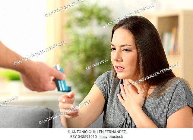 Asthmatic girl suffering an asthma attack receiving an inhaler at home