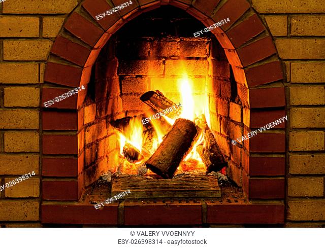 burning wooden logs in brick fireplace in country cottage