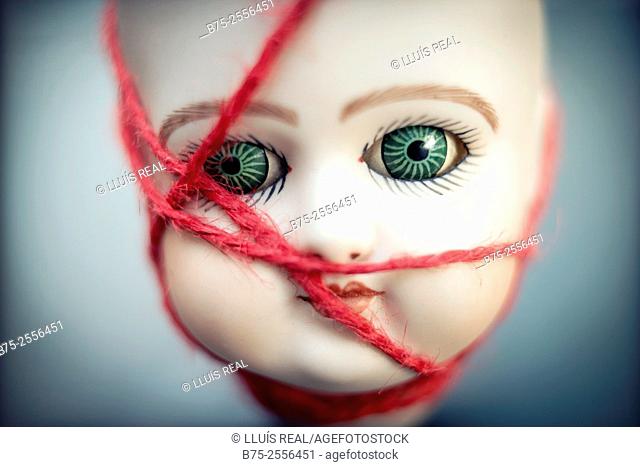 Head of antique porcelain doll tied with a red rope