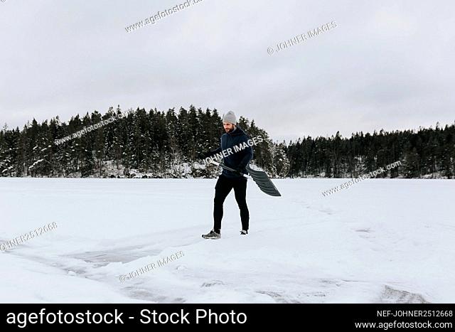 Man clearing snow on frozen lake