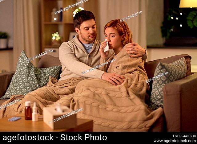sick young couple with tissue blowing nose at home