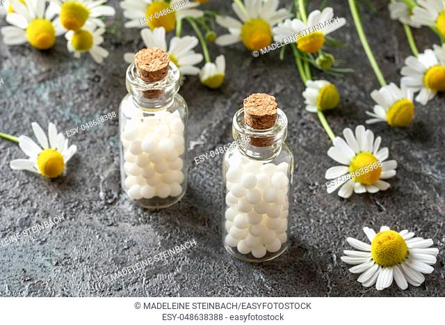 Bottles of homeopathic remedies with fresh chamomile flowers