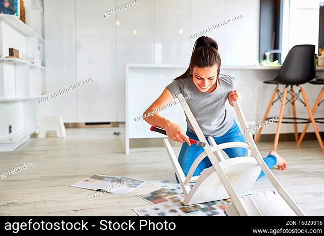Frau als Heimwerker zu Hause beim Stuhl lackieren oder Streichen als Upcycling
