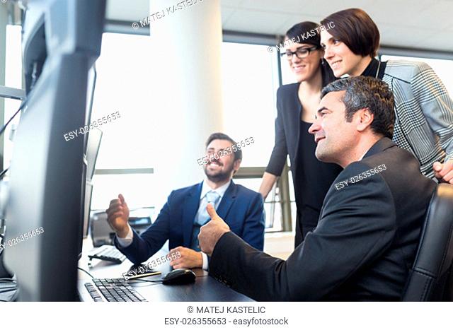 Successful business team looking at data on multiple computer screens in corporate office. Business, entrepreneurship and team work