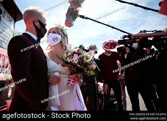 05 May 2020, North Rhine-Westphalia, Duesseldorf: The bridal couple Janine and Philip Scholz stand at the wedding ceremony in the drive-in cinema with face mask...