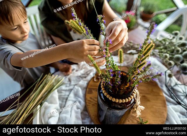 Son and mother holding plant while making decorative flower pot