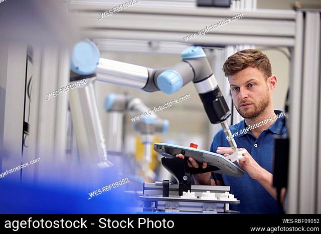 Engineer testing robotic arm using equipment in industry