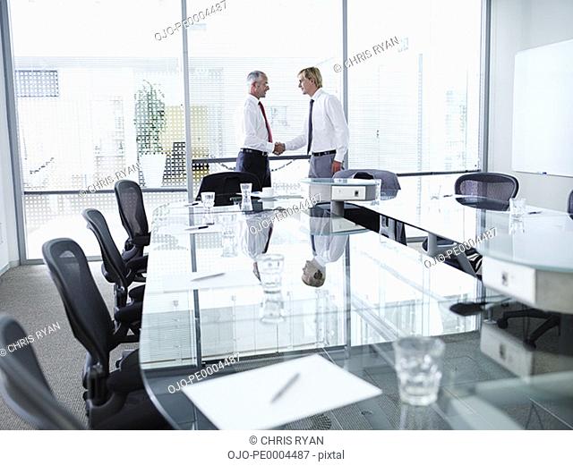 Two businessmen meeting and shaking hands in a boardroom