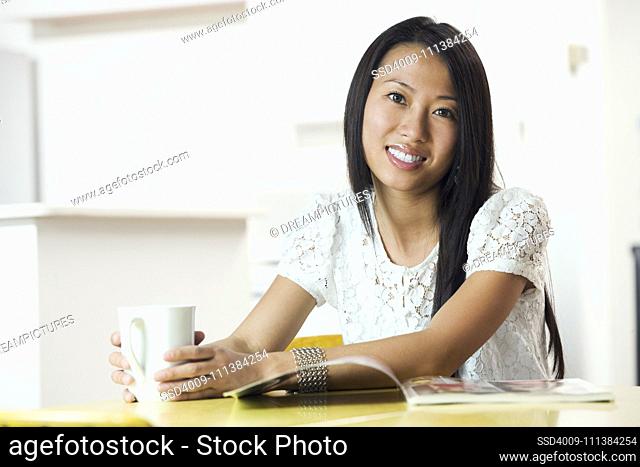 Asian woman holding coffee mug at table