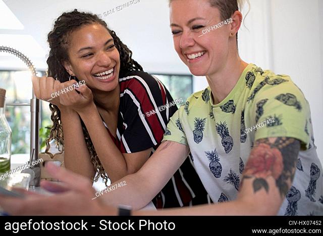 Happy young women friends laughing in kitchen