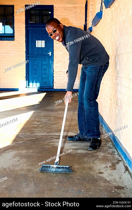 Soweto, South Africa - July 21, 2012: African man performing community service volunteer cleaning work at township school