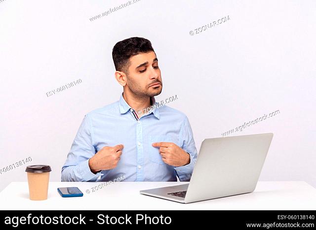 This is me. Selfish businessman sitting office workplace, pointing himself and looking self-confident arrogant at laptop screen