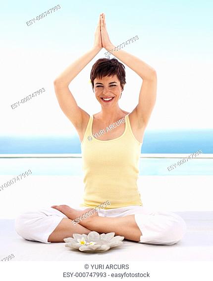 Young woman practicing yoga with hands raised in the air