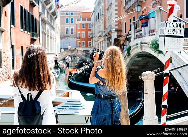 Two young girls stand on the gondola service and take pictures of local attractions