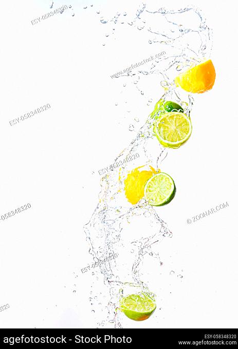 Fresh limes and lemons with water splash in midair, isolated on white background. Refreshment concept