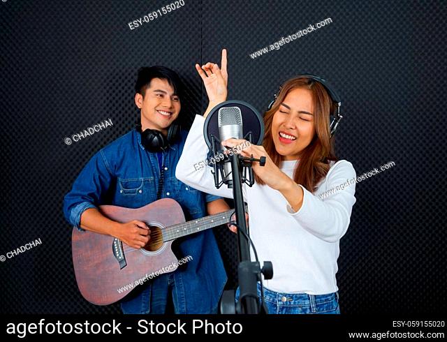 Young asian woman dance, swaying, and lifting her arms rhythmically while singing. Musicians producing music in professional recording studio