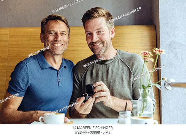 Portrait of gay couple with wedding ring in cafe