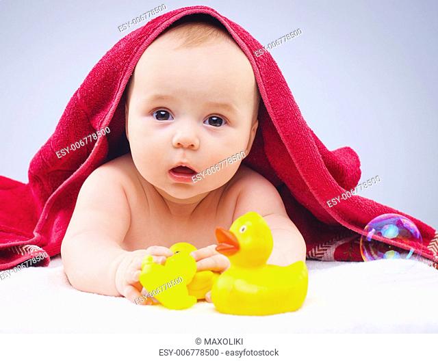 Eight month baby girl playing with rubber duck in studio