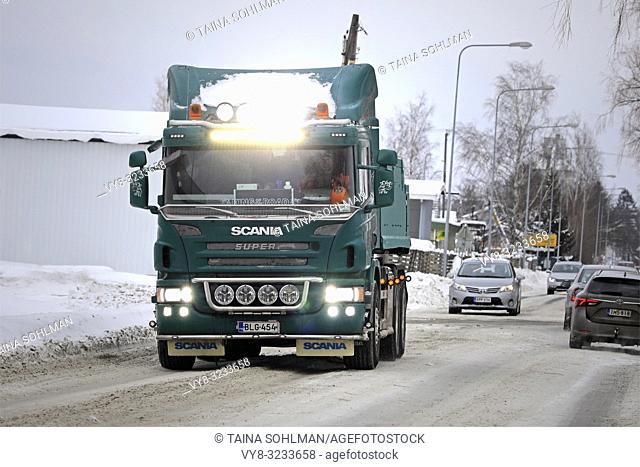 Salo, Finland - February 2, 2019: Customised green Scania P420 truck, high beams and led light bar lit up briefly, hauls away snow cleared from city