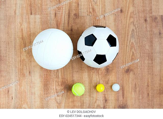 sport, fitness, game, sports equipment and objects concept - close up of different sports balls set on wooden floor from top
