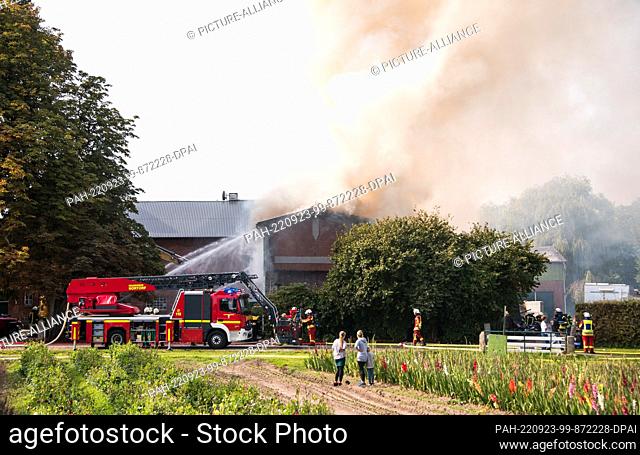 23 September 2022, Schleswig-Holstein, Borgdorf-Seedorf: Firefighters extinguish a burning barn with the help of a turntable ladder