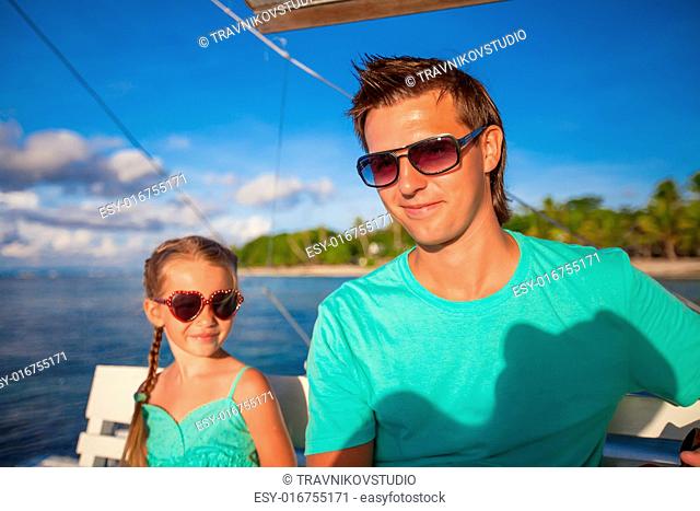 Little adorable girl with young dad relax while sailing on the boat