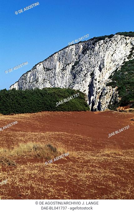 Characteristic red soil of Lefkada island, with a rocky hill in the background, Greece