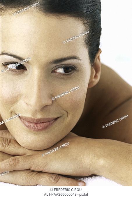 Woman smiling, head on hands, close-up