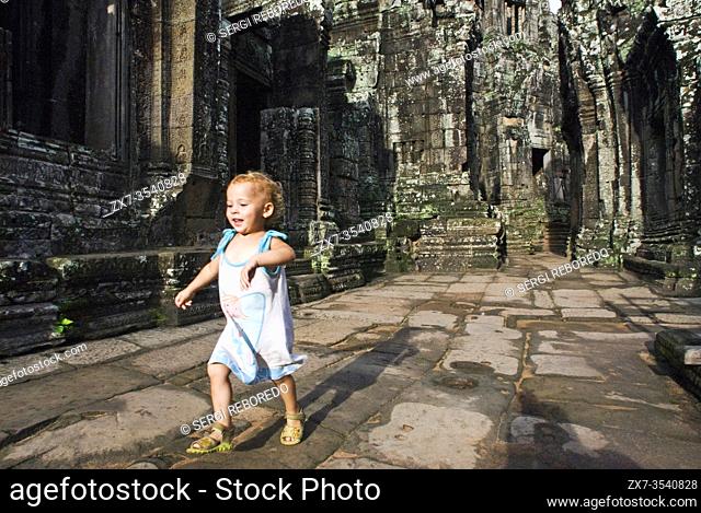 Girl walking alone in Bayon temple. Angkor Thom. Angkor Thom was built as a square, the sides of which run exactly north to south and east to west