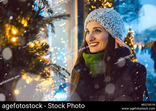 Woman looking in shop window on Christmas shopping gifts