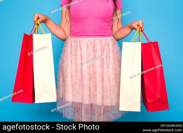 Portrait of young happy smiling woman with shopping bags, over blue background. Purchase, sale and people concept