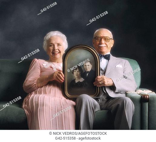 Elderly couple holding photo from when they were just married