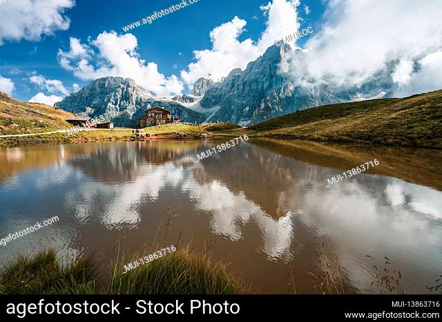 Baita Segantini mountain with Cimon della Pala peak, refuge reflected in alpine lake. Rolle pass, Trentino province, Italy, Europe