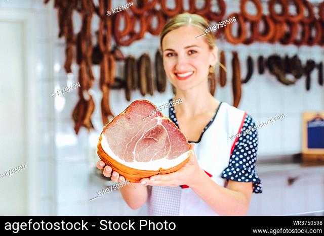 Saleswoman holding ham in her hand in butchery shop, focus on meat