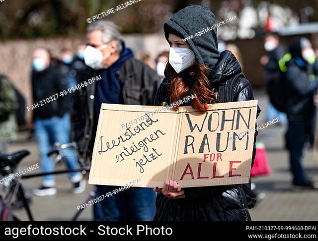 27 March 2021, Berlin: A participant in the Housing Action Day demonstration of the Action Alliance Against Displacement and Rent Madness holds a placard in her...
