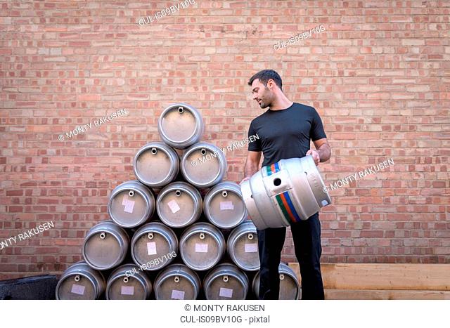 Brewer stacking barrels in small brewery