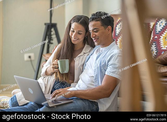 Young boy and girl together at home enjoying laptop computer sitting on the floor smiling and laughing - new life married people in love and relationship have...