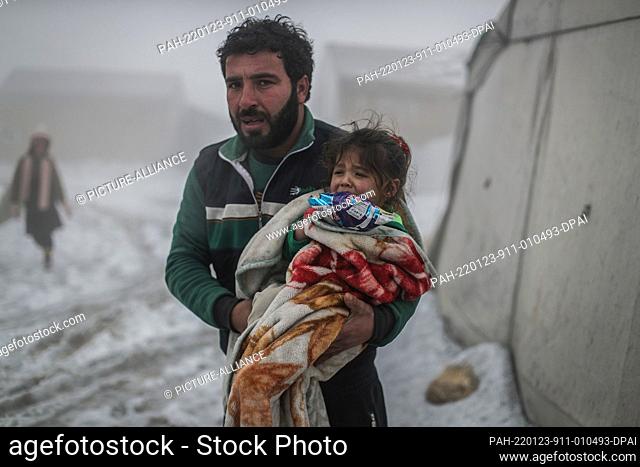 23 January 2022, Syria, Salqin: A man waits for an ambulance to arrive after a heater fell on his daughter and burned her during a heavy snowfall in a camp for...