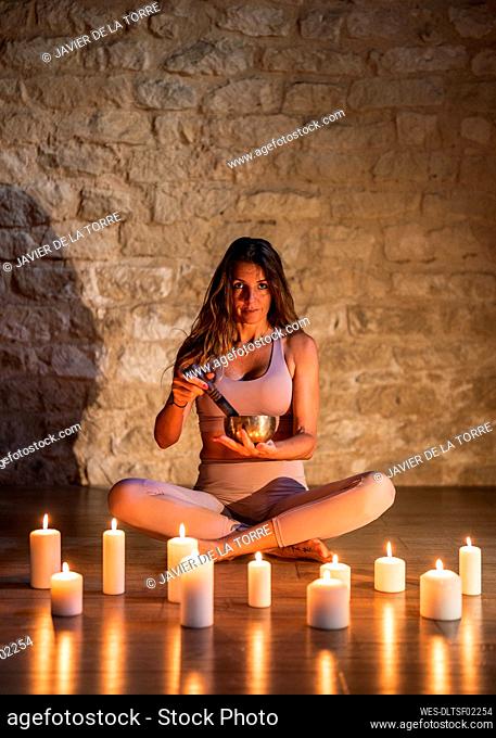 Mature woman with rin gong sitting by candle on floor