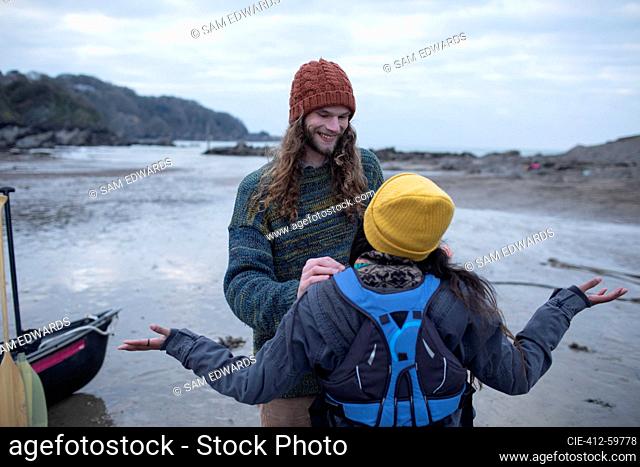 Happy young couple preparing for canoeing on beach