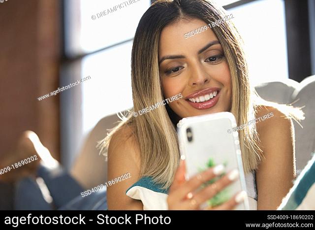 Close up of a young girls smiling while laying on couch and having a video call on her phone
