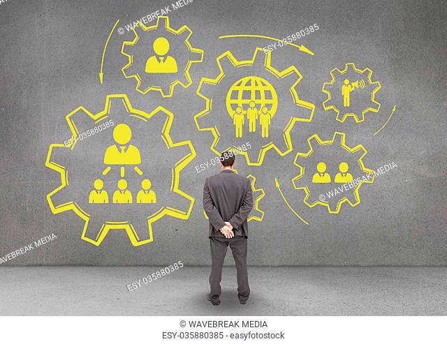 Business man standing against people in cogs graphics against grey background