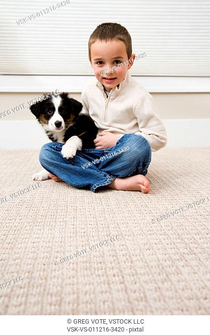 Boy sitting with puppy on carpet
