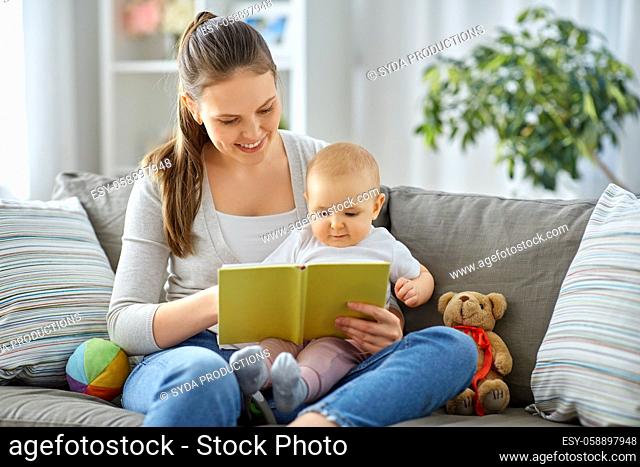 happy mother reading book to little baby at home