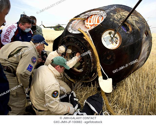Russian support personnel work to help get crew members out of the Soyuz TMA-22 spacecraft shortly after the capsule landed with Expedition 30 Commander Dan...