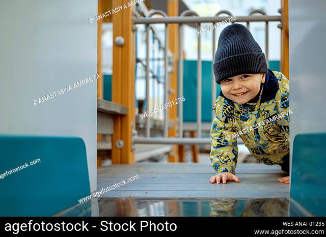 Smiling cute boy crawling at playground