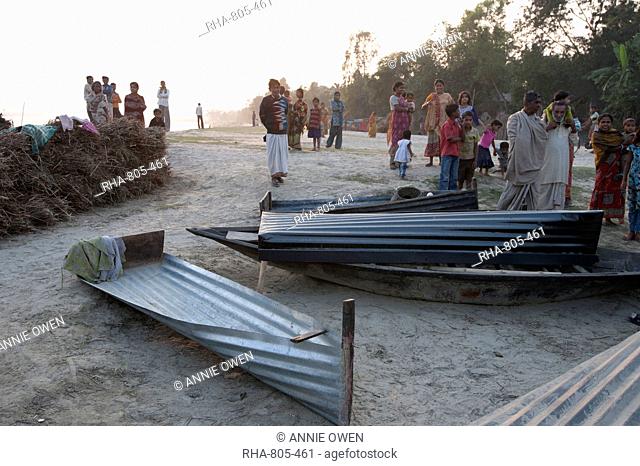 Villagers surrounding small boats made from single sheets of corrugated iron, lying on the banks of the River Hugli River Hooghly, West Bengal, India, Asia