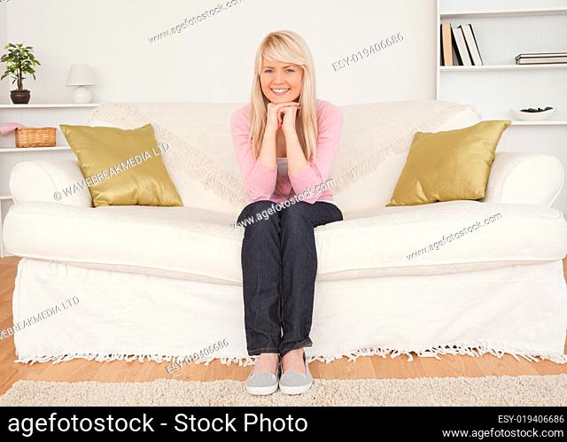 Beautiful blonde woman posing while sitting on a sofa