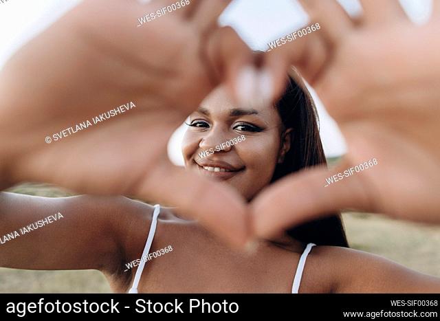 Smiling woman making heart shape with hand