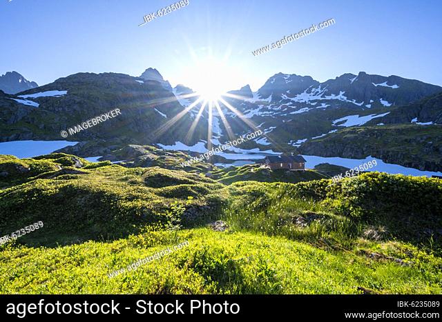 Sun shining on mountains with snow, mountain range at the mountain hut Trollfjord Hytta, at the Trollfjord, Lofoten, Nordland, Norway, Europe